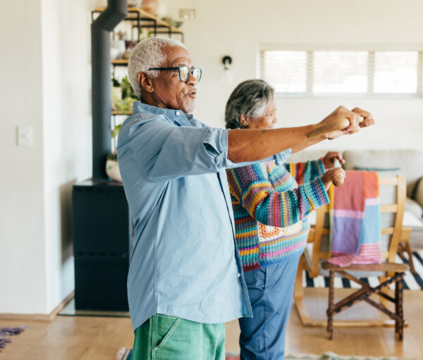 Two older adults doing exercises at home.